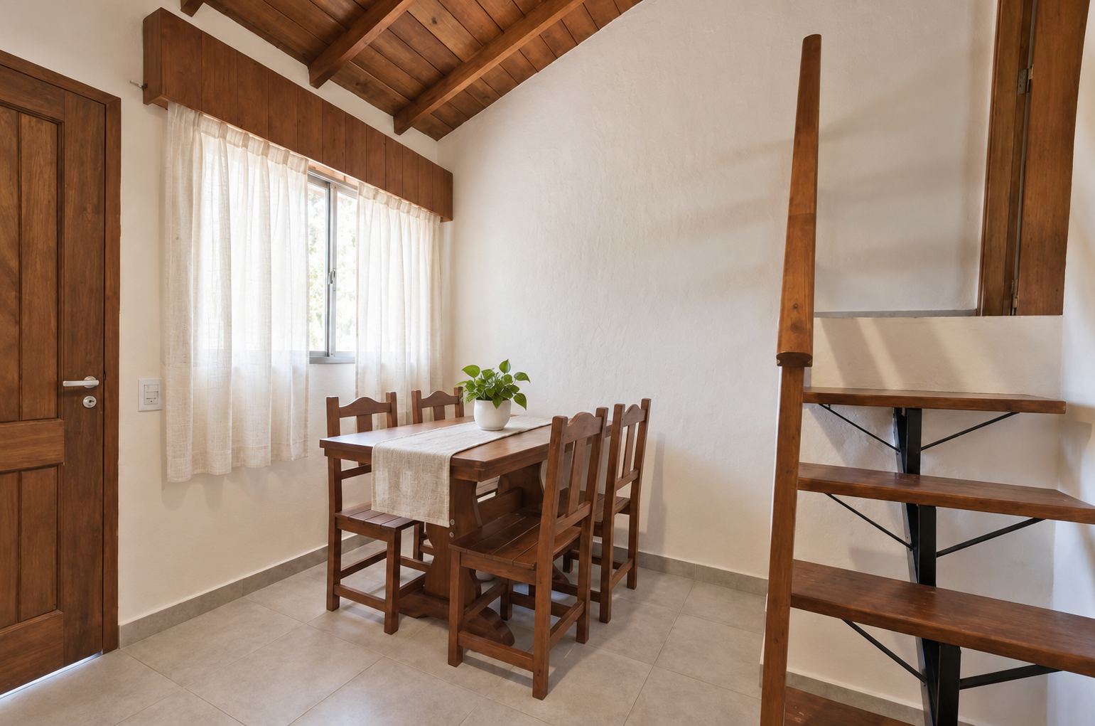 Comedor con mesa y sillas de madera junto a la escalera y la ventana